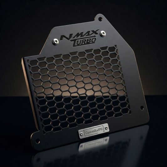 Close-up studio shot of the CustomradPH Yamaha NMAX Tech Max Radiator Cover. This black powder-coated CNC steel motorcycle accessory features an aggressive honeycomb mesh design, a precision-cut NMAX TURBO logo at the top, and a brushed metal CustomradPH badge at the bottom, showcasing its premium exterior styling and durable construction.