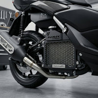 The CustomradPH Yamaha NMAX Tech Max Radiator Cover installed on the right-side engine bay of the scooter. This black powder-coated CNC steel motorcycle accessory features a rugged honeycomb mesh design that aligns perfectly with the bike's factory side panels and exhaust routing. The direct-fit, plug-and-play cover prominently displays a precision-cut NMAX TURBO logo and brushed metal CustomradPH badge, giving the NMAX a sharper, more finished profile.